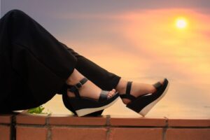 Stylish black sandals on a wall with a warm sunset backdrop, exuding elegance. - Photo by José Martin Segura Benites on Pexels