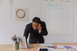 Businessman in an office making a call while working on a laptop with office supplies. - Photo by RDNE Stock project on Pexels