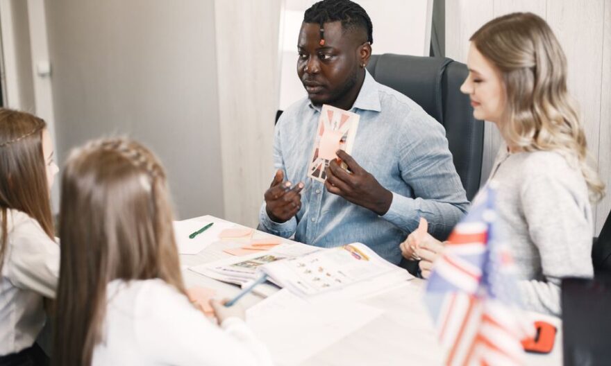Teacher guiding diverse students in an English language lesson with a British flag card. - Photo by Gustavo Fring on Pexels