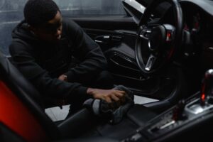 A man wipes the interior of a car for a thorough cleaning, focusing on detailing and maintenance. - Photo by Tima Miroshnichenko on Pexels
